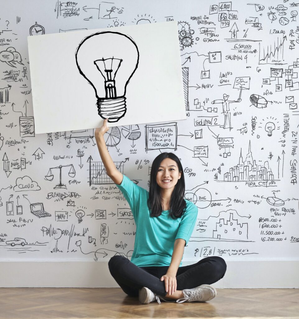 A girl draw a Light bulb in a white board
