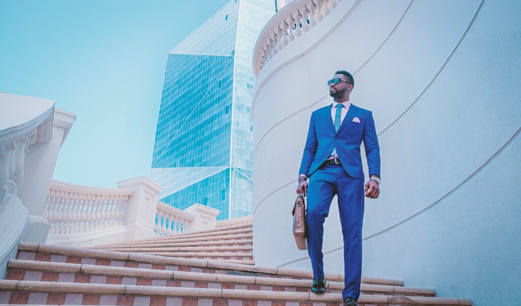A guy wearing a blue full suit  coming up the stairs