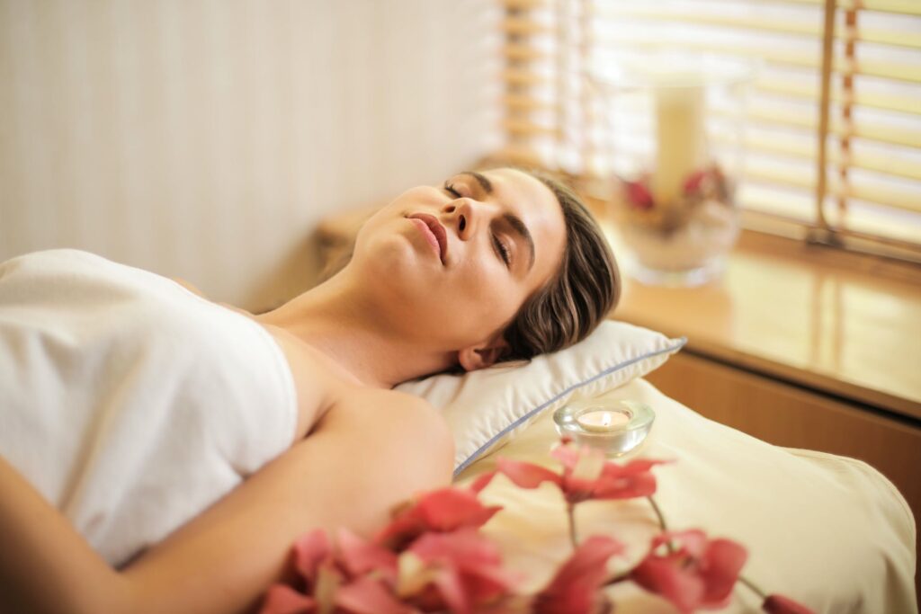 A lady lying on a bed with closed eyes by taking Exclusive Wellness Retreats experience