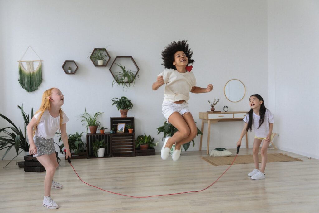Three girls playing while a girl jumping over rope 