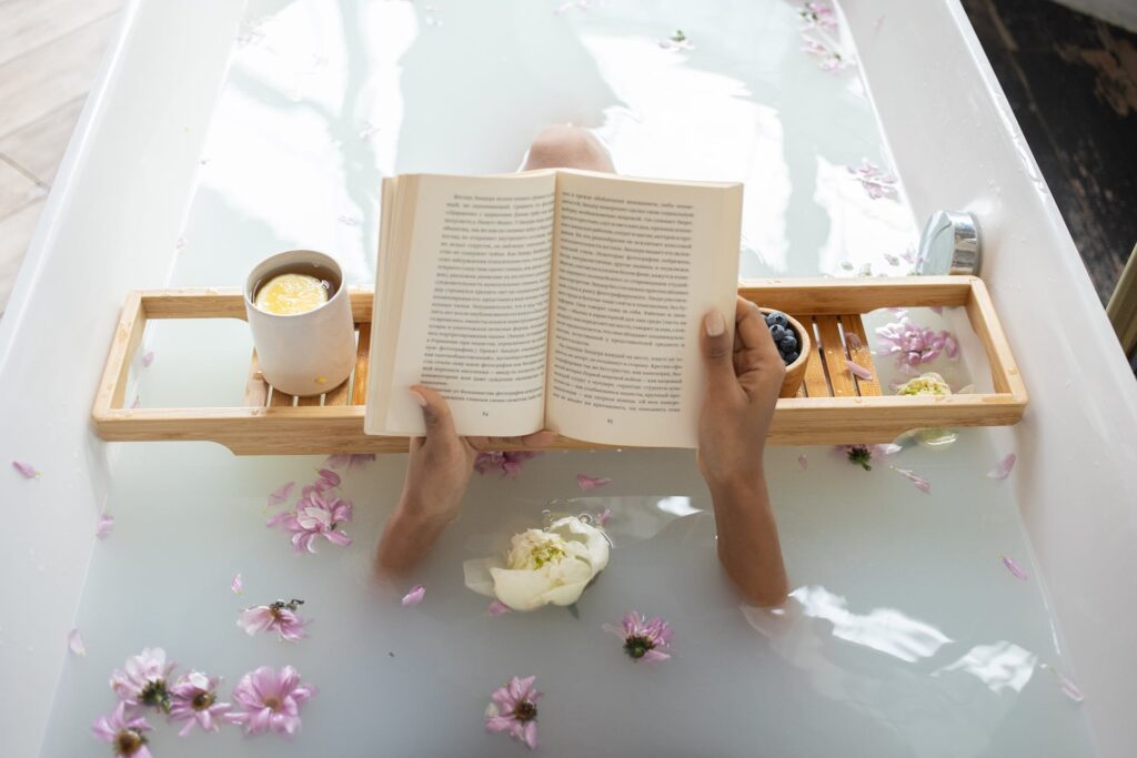 A women taking a bath in a bath tub while reading a book
