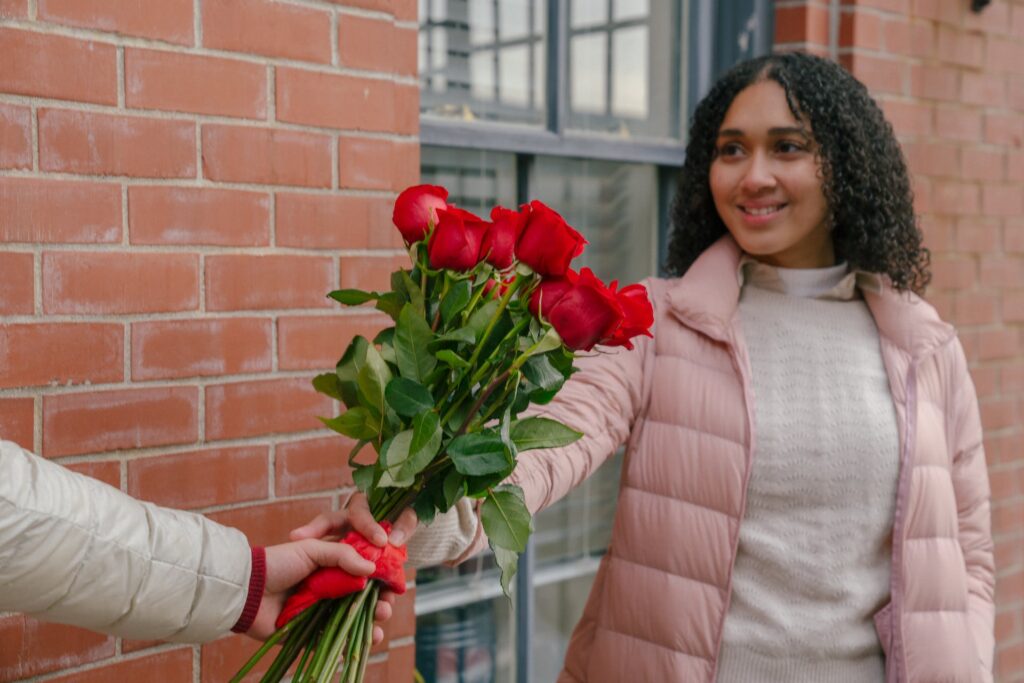 A boy giving a red rose bouquet for his girl