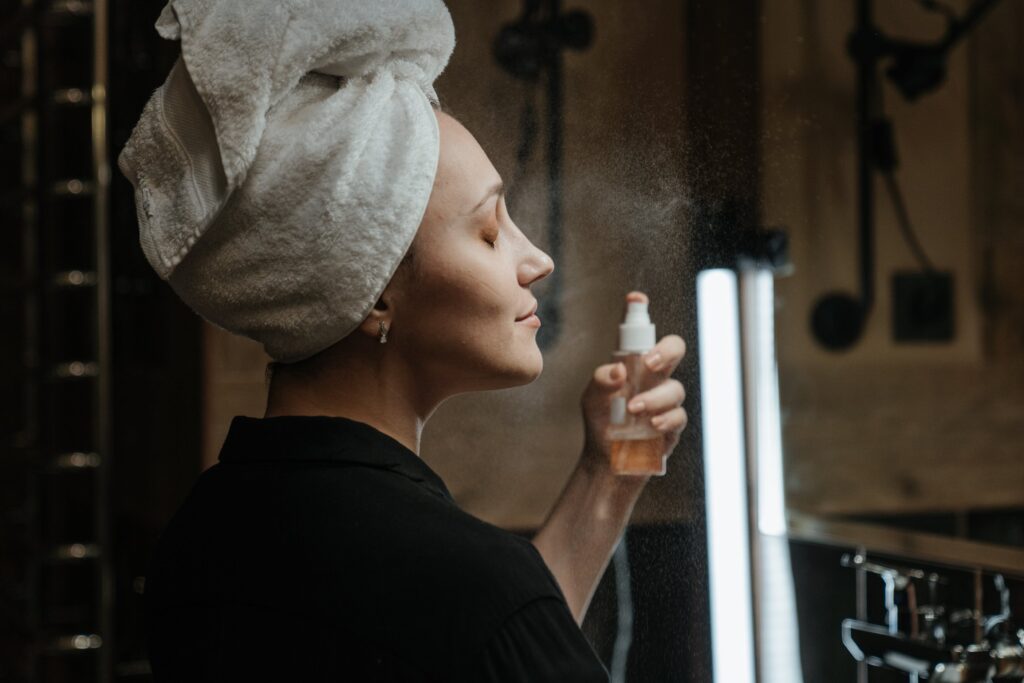 A woman spraying a beauty product to her face