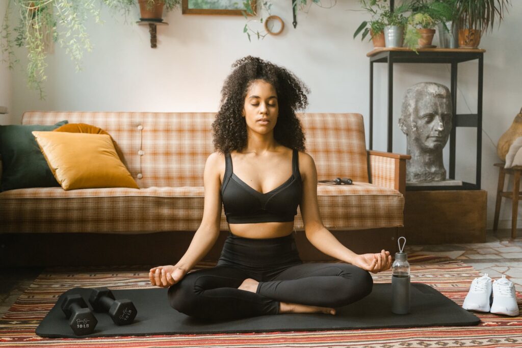 A woman practicing quick mindfulness exercises sitting on a black yoga mat