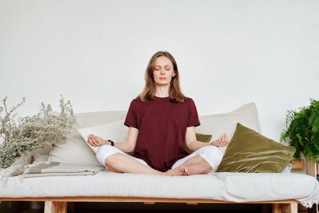 A lady siting on a couch practicing meditation 
