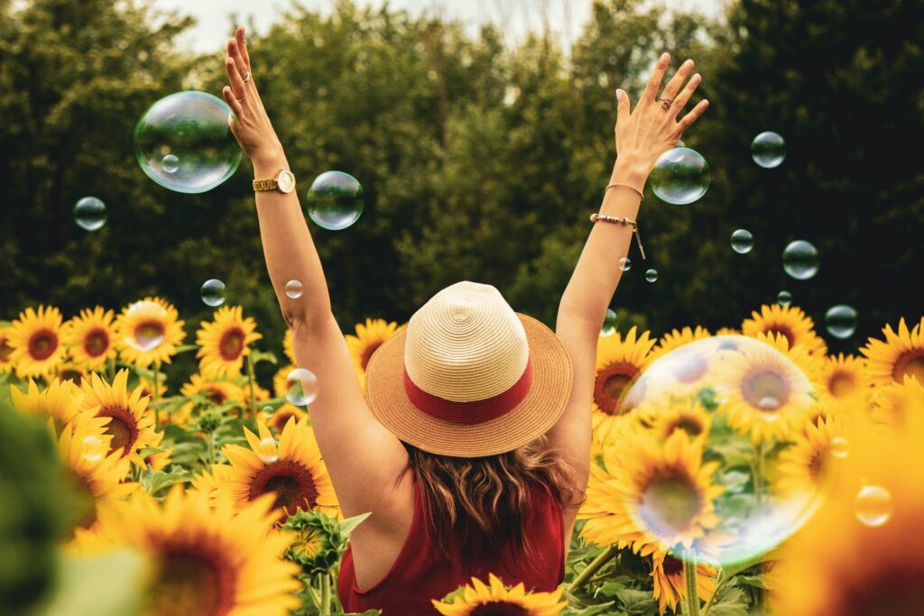 A girl raising her both hands up in a sunflower garden