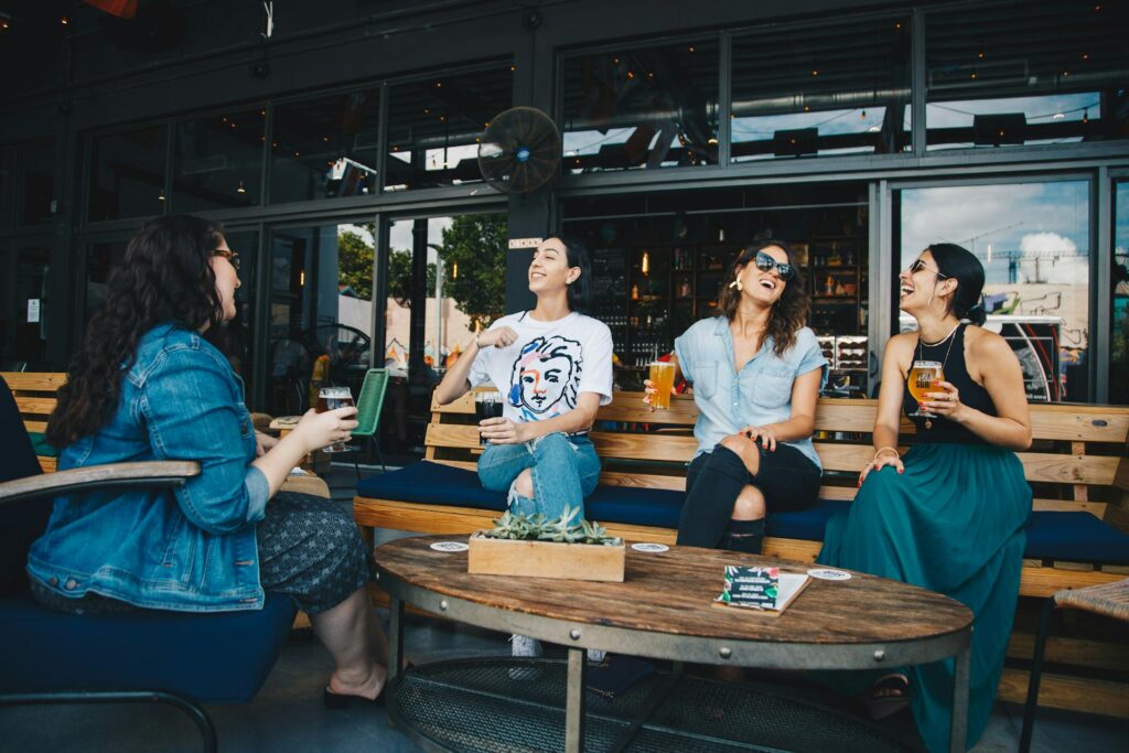 Four girls sitting on a wooden bench in a cafe