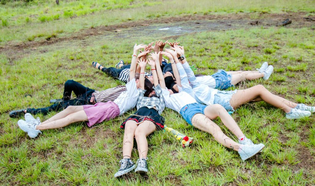 A group of friends forming a circle while laying on the grass showing colourful friendship they have