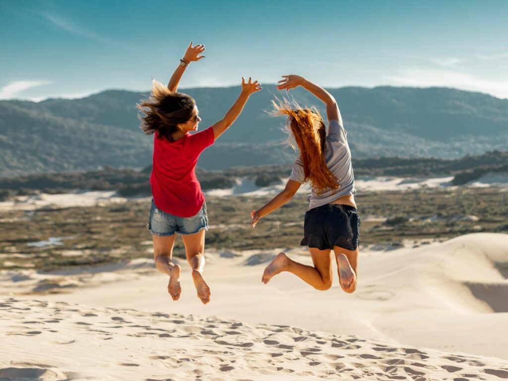 Two girls jumping while raising their hands up