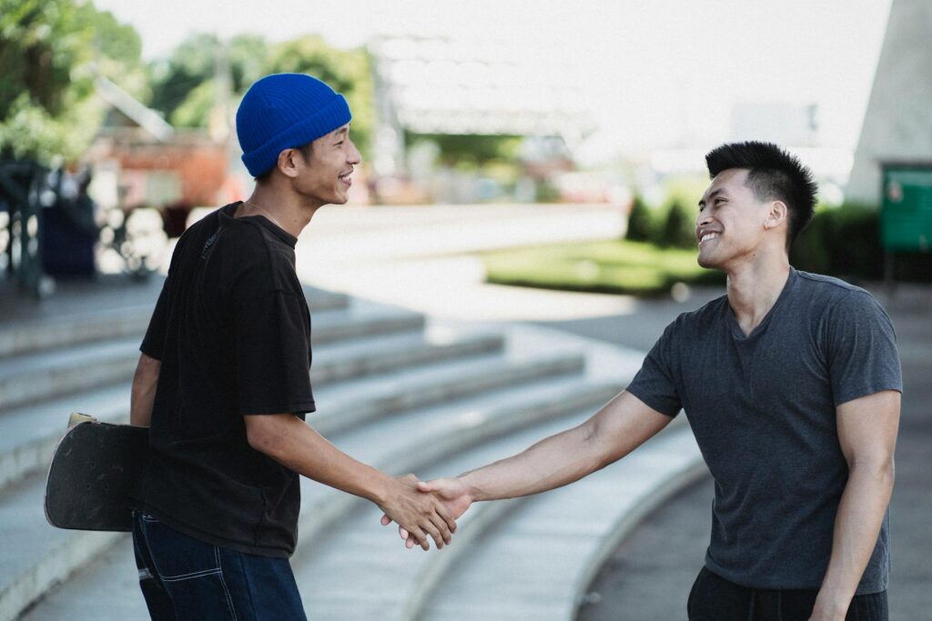 Two boys shaking hands on the street showing signs people respect you
