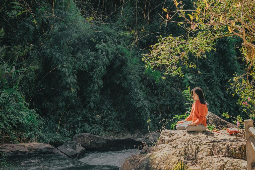 A woman practicing meditation near a river  for yoga motivation