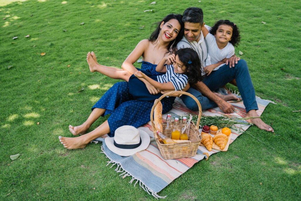Mom, dad and kids sitting on a picnic mat
