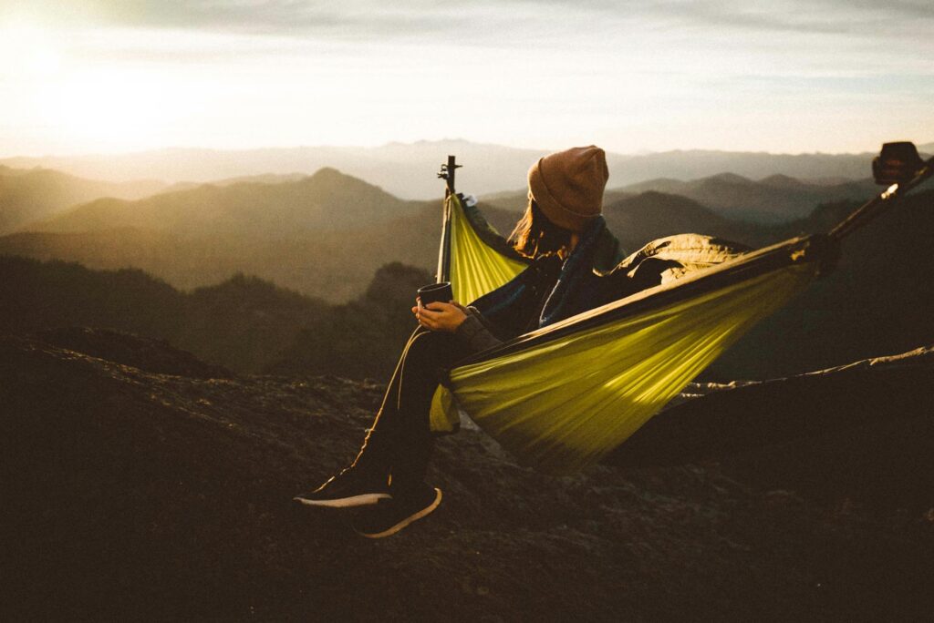 A girl sitting in a hammock on a mountain range