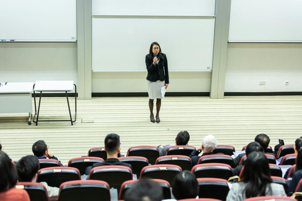 A lady wearing a black jacket addressing an audience
